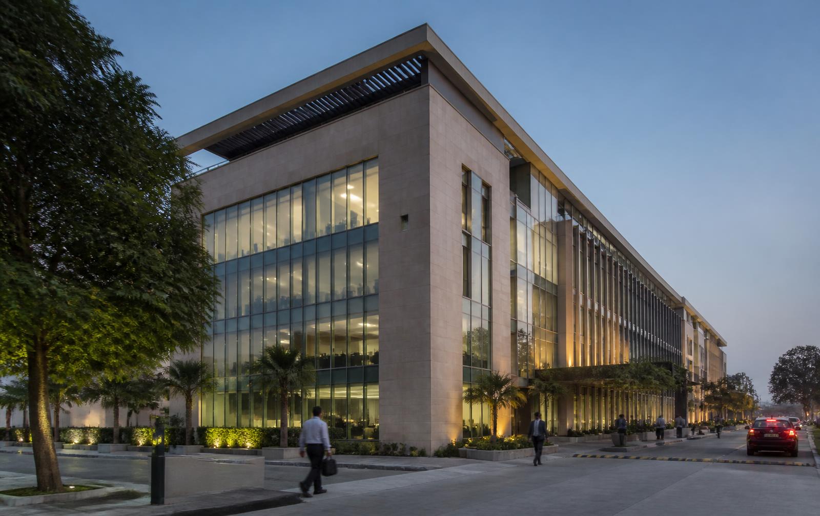 Contemporary stone and glass office building in a landscaped Pakistani business district at blue hour